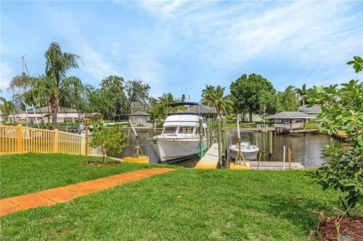Dock area featuring a water view, fence, a lawn, and boat lift
