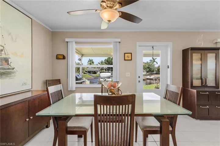 Dining space with ornamental molding, ceiling fan, and light tile patterned flooring