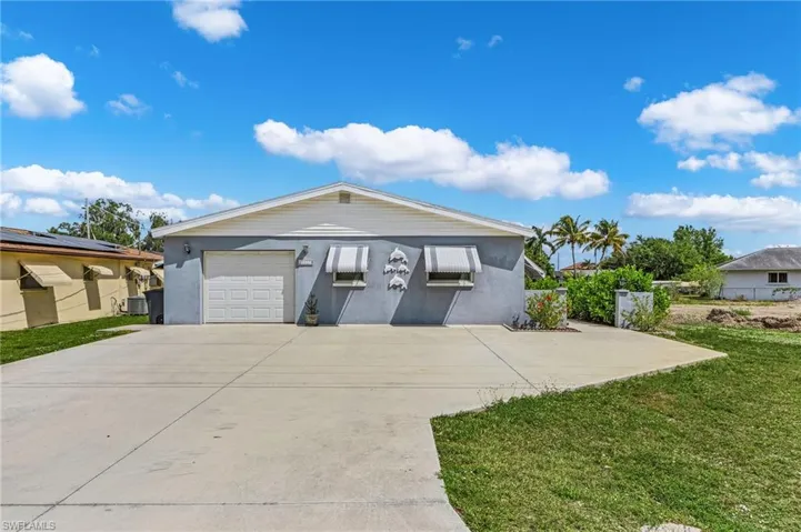 Ranch-style home with central AC, stucco siding, a front yard, a garage, and concrete driveway