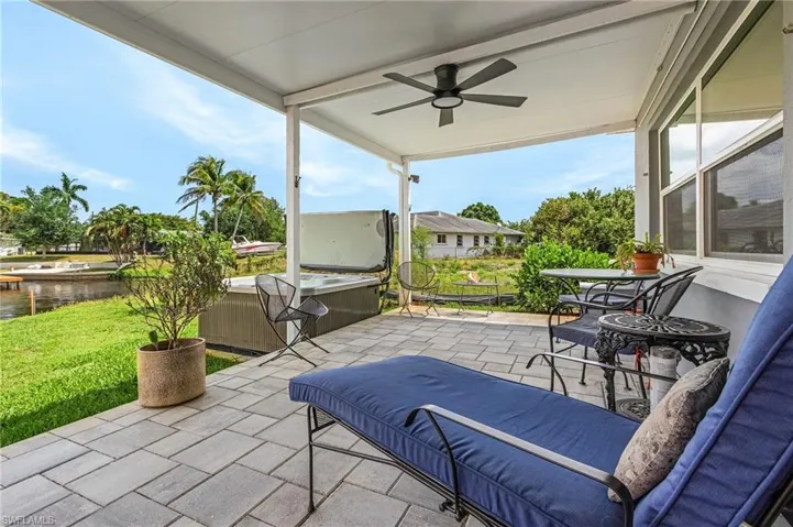 View of patio / terrace with a water view, a ceiling fan, and a hot tub