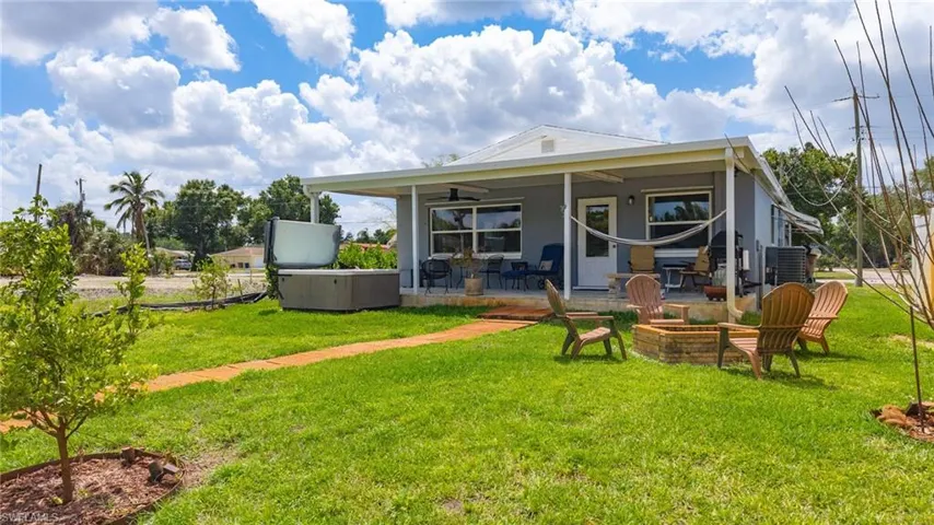 Rear view of house with an outdoor fire pit, a patio, ceiling fan, and a lawn