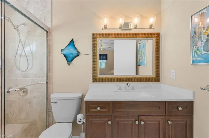 Full bathroom with a shower stall, vanity, a ceiling fan, and toilet