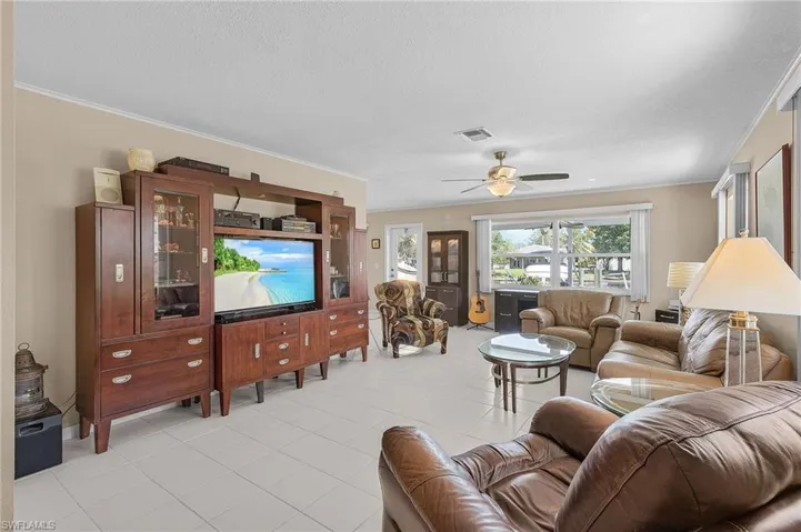 Living area with ornamental molding, visible vents, a ceiling fan, and a textured ceiling