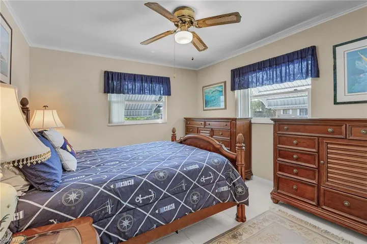 Bedroom featuring light tile patterned floors, ornamental molding, and ceiling fan