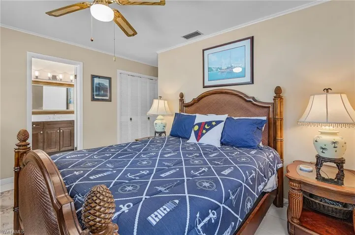 Bedroom featuring visible vents, a closet, ornamental molding, ceiling fan, and ensuite bath