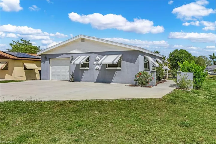 View of front facade with an attached garage, driveway, stucco siding, and a front lawn
