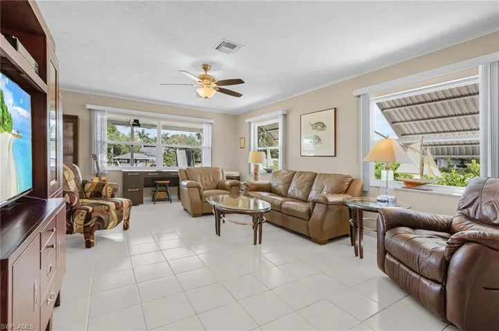 Living room featuring a textured ceiling, ceiling fan, ornamental molding, and visible vents