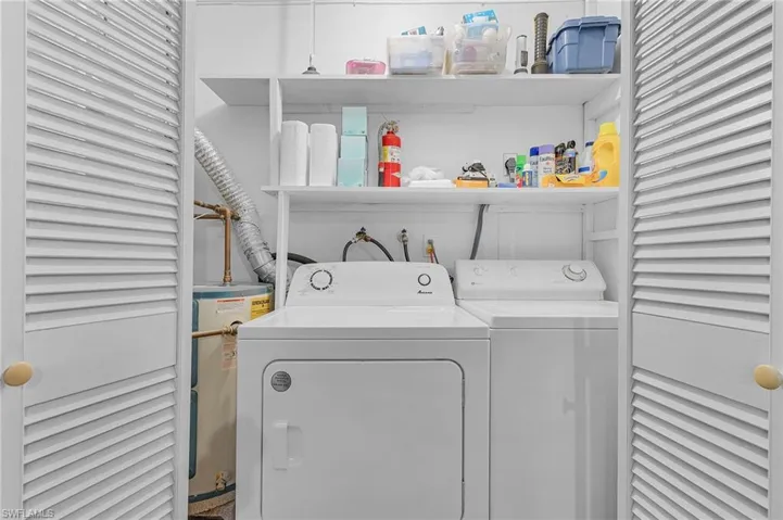 Clothes washing area featuring laundry area, separate washer and dryer, and water heater