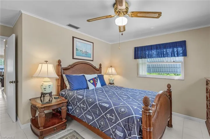 Bedroom with tile patterned floors, visible vents, baseboards, and ornamental molding