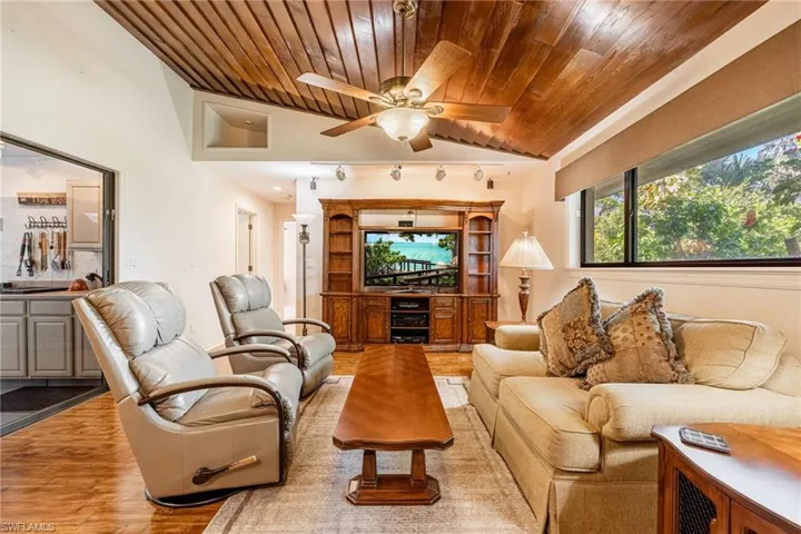 Living room with hardwood / wood-style flooring, ceiling fan, wooden ceiling, and vaulted ceiling