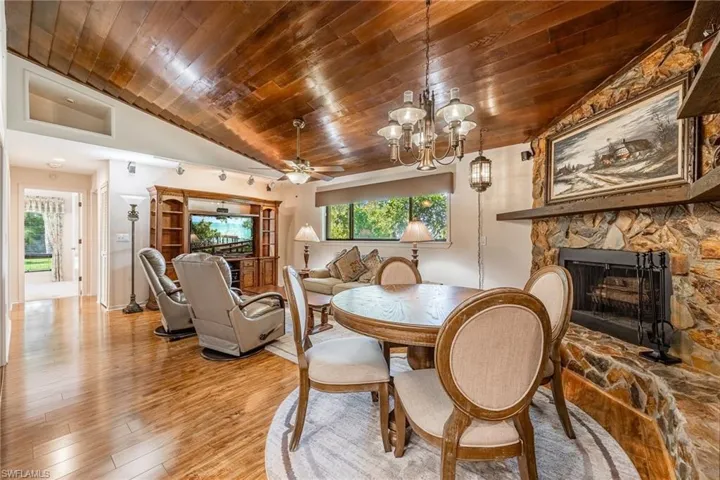 Dining space with wooden ceiling, a stone fireplace, wood flooring, and vaulted ceiling
