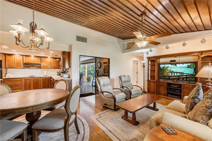 Living room with ceiling fan with notable chandelier, light hardwood / wood-style floors, and wooden ceiling