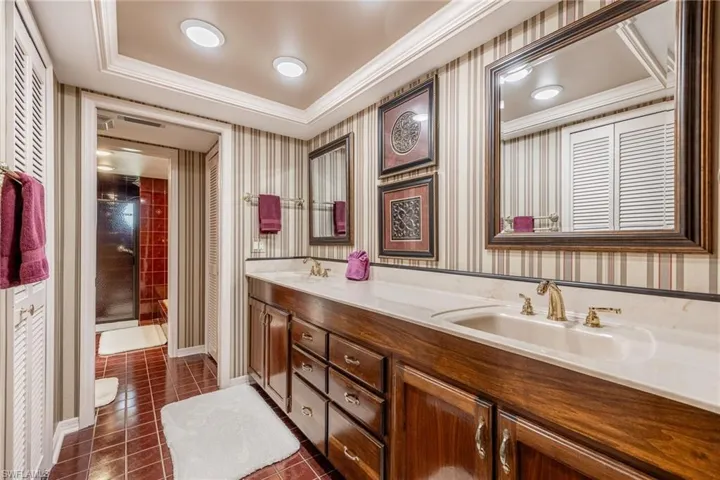 Bathroom with tile patterned floors, vanity, a raised ceiling, and a tile shower