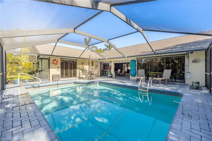 View of pool with screen enclosure and a patio area