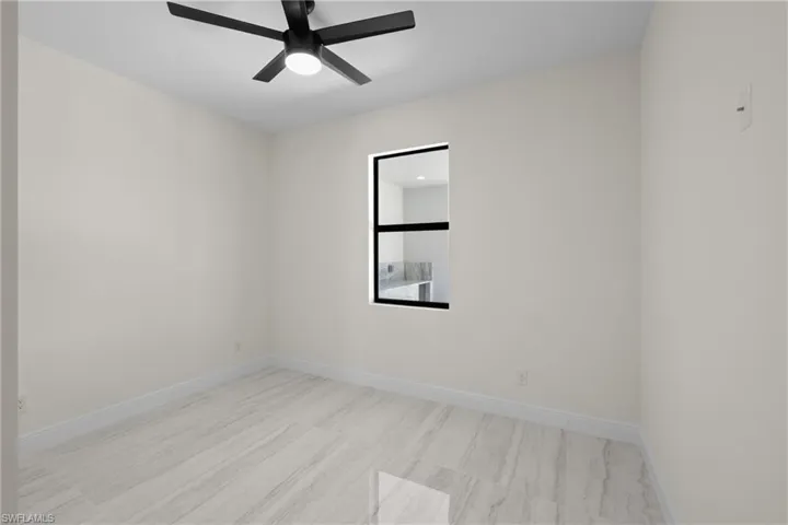 Unfurnished room with a ceiling fan, baseboards, and light wood-type flooring