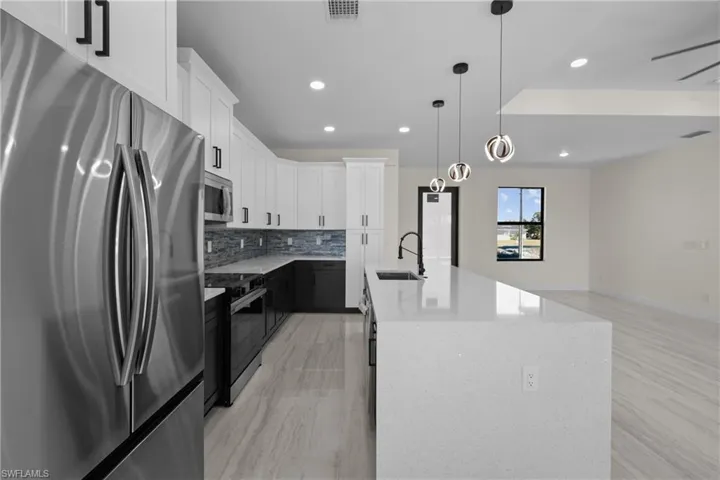 Kitchen with visible vents, a kitchen island with sink, a sink, stainless steel appliances, and tasteful backsplash