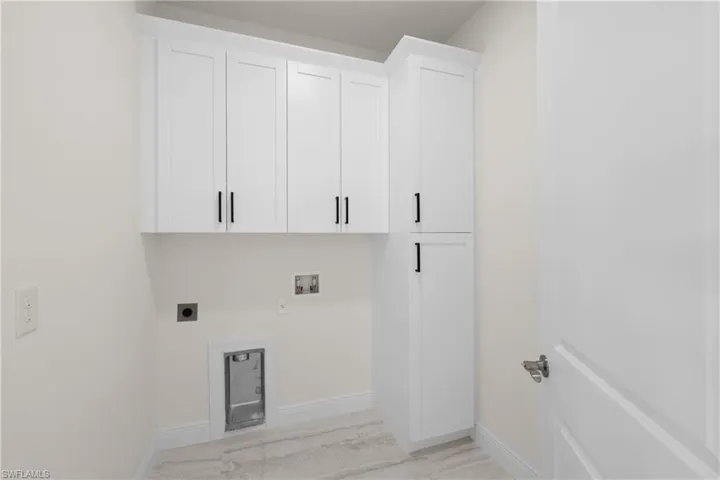 Washroom with electric dryer hookup, baseboards, cabinet space, and washer hookup