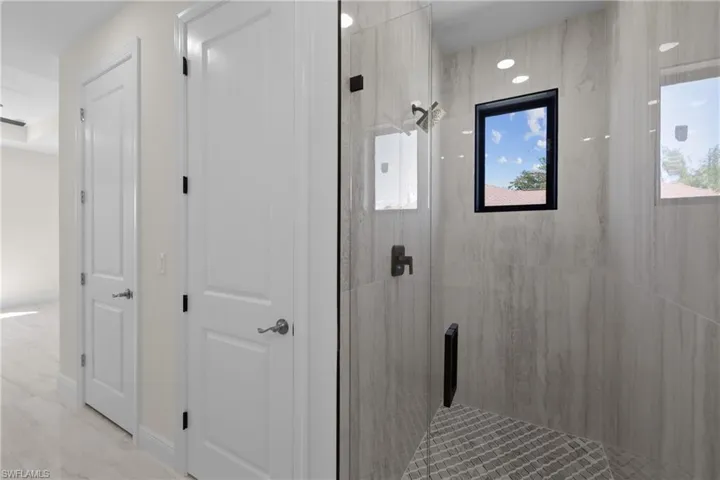 Full bath with marble finish floor and a shower stall