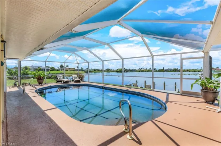 View of pool with a water view, screen enclosure, and a patio area