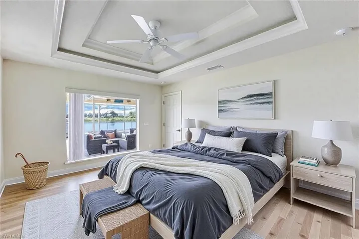 Bedroom with a tray ceiling, baseboards, visible vents, and light wood-style flooring