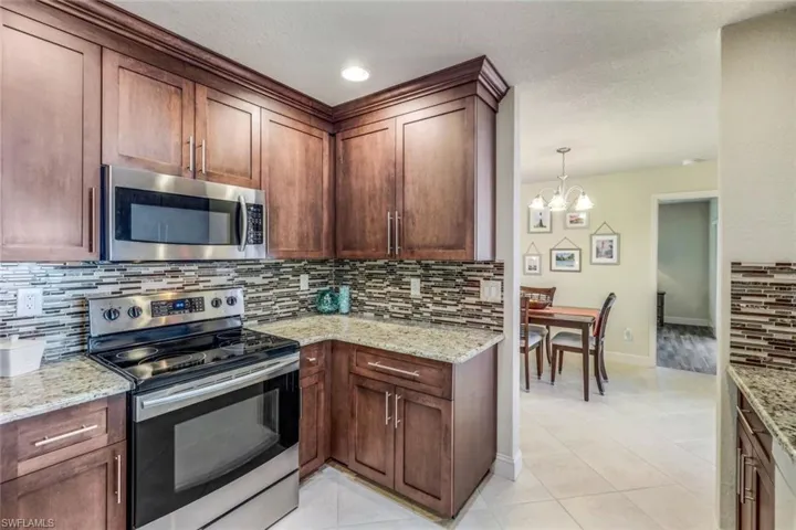 Kitchen featuring light tile floors, backsplash, and appliances with stainless steel finishes
