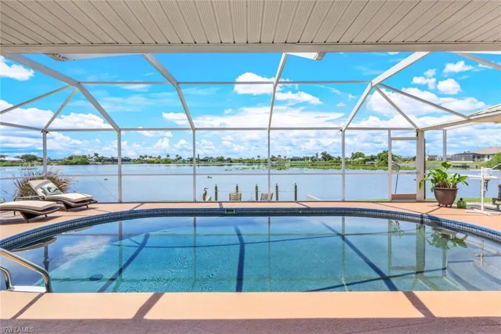 View of pool featuring screen enclosure and a water view