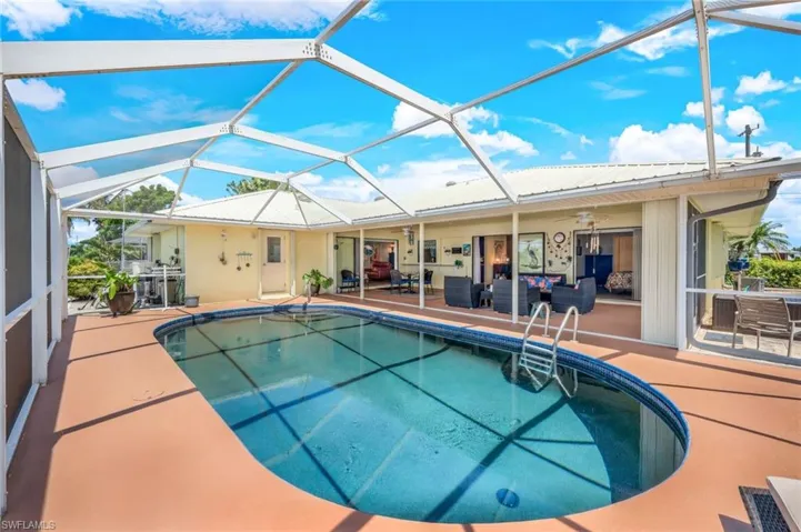 View of swimming pool featuring screen enclosure, a patio area, and ceiling fan