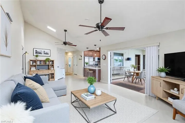 Living area with light tile patterned floors, high vaulted ceiling, and ceiling fan