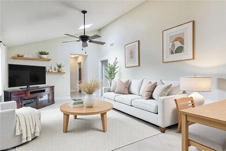 Tiled living area with visible vents, lofted ceiling, and a ceiling fan