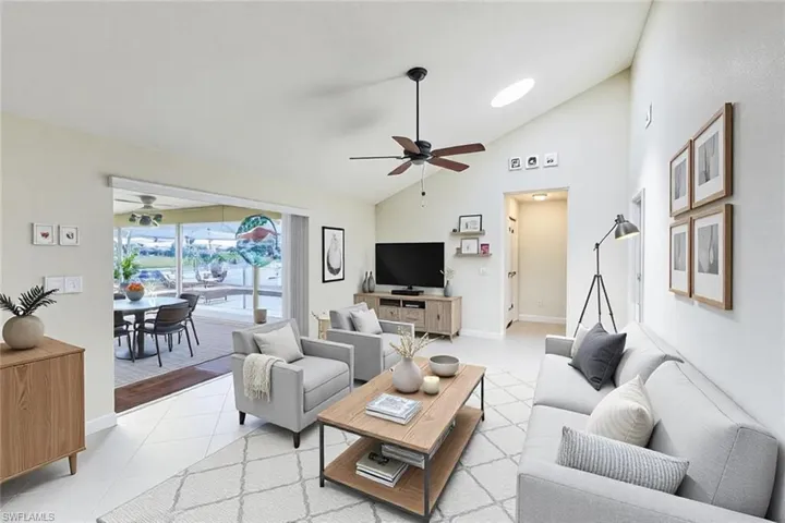 Living room featuring light tile patterned flooring, baseboards, high vaulted ceiling, and a ceiling fan