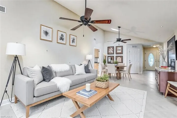 Living area featuring baseboards, a ceiling fan, visible vents, and high vaulted ceiling