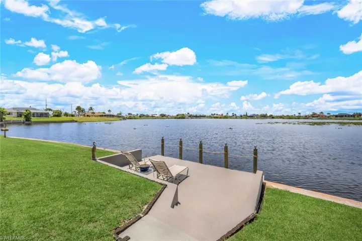 View of concrete dock featuring a yard and a water view. Hose spigot and electric at the dock.