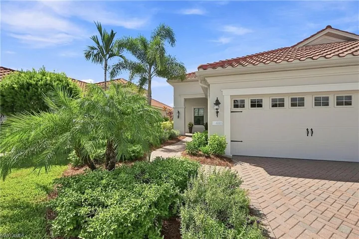 Mediterranean-style exterior featuring a tile roof, paver driveway, and a garage with decorative hardware