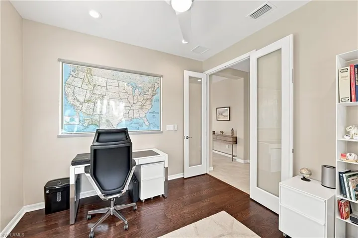 Dark wood-finish flooring, recessed lighting, ceiling fan, and French doors with frosted glass panels