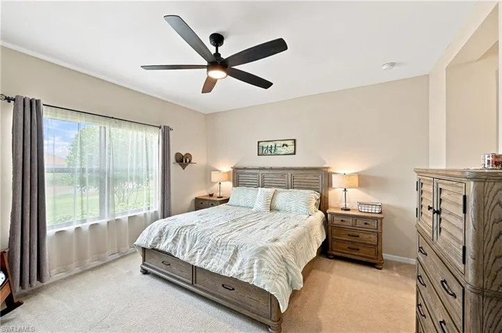 Wall-to-wall carpeting with a large window, a ceiling fan, and neutral wall paint