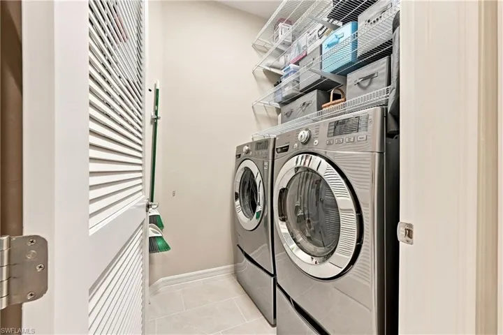 Dedicated laundry area with front-loading appliances, overhead wire shelving, and tiled flooring