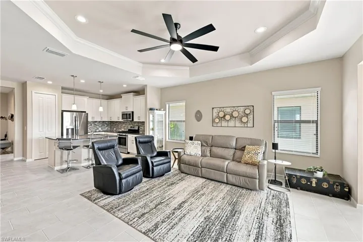 Open-concept living area with tray ceiling, recessed lighting, and a modern ceiling fan