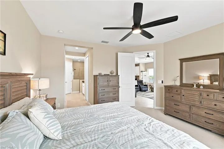 Recessed lighting, ceiling fan, neutral wall tones, carpeted flooring, and a doorway opening to an additional room with a ceiling fan