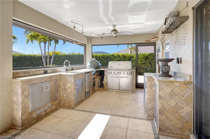 Outdoor kitchen with built-in grill, Big Green Egg smoker, and everything needed to entertain poolside.