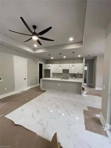 Unfurnished living room featuring a tray ceiling, recessed lighting, and a ceiling fan
