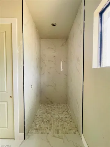 Full bathroom featuring marble look tile flooring and a marble finish shower
