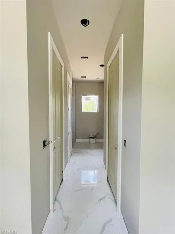 Hall with light marble finish flooring and baseboards