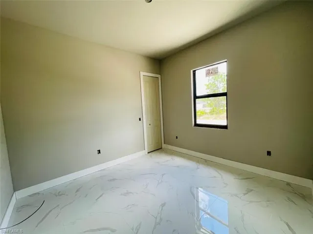 Spare room with baseboards and light marble finish floors