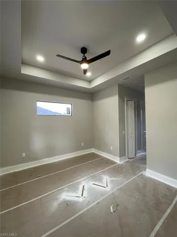 Empty room with ceiling fan, recessed lighting, and a raised ceiling
