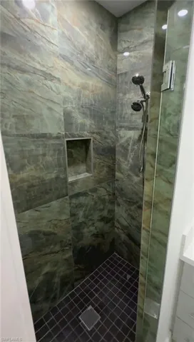 Full bath featuring tiled shower and vanity