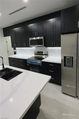 Kitchen featuring dark cabinetry, appliances with stainless steel appliances