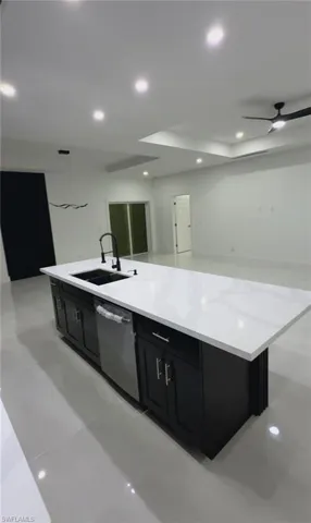 Kitchen featuring a kitchen island with sink, a ceiling fan, dark cabinets, dishwasher, and recessed lighting