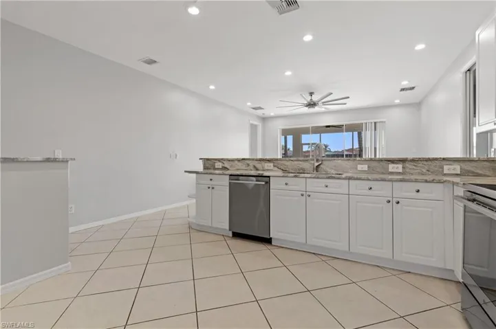 Kitchen featuring white cabinets, light stone countertops, stainless steel appliances, recessed lighting, and light tile patterned floors