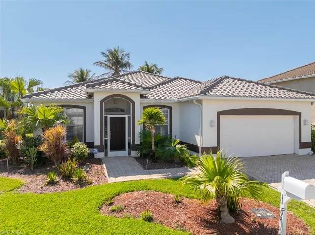 Mediterranean / spanish house featuring an attached garage, a tile roof, stucco siding, and driveway