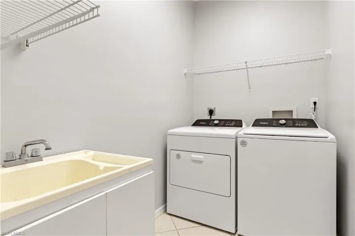 Laundry area with washing machine and dryer and light tile patterned floors